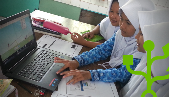 Four girls using one laptop. One of them is using the trackpad.